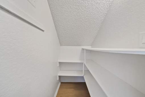 A white hallway with a bench and shelves.