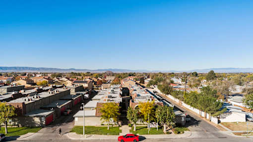 A red car is parked on the side of a road in a suburban area.