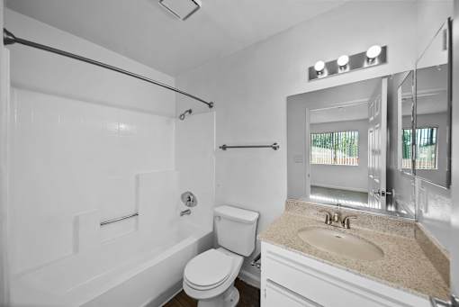 A white bathroom with a toilet, sink, and bathtub.