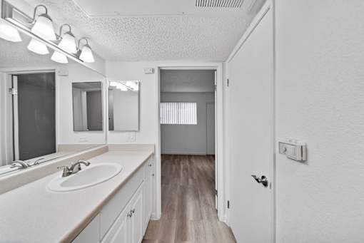 A bathroom with a sink, mirror, and lighting fixtures.