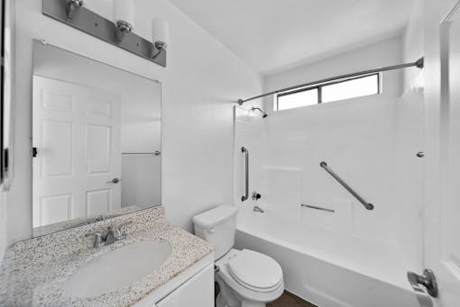 A white bathroom with a sink, toilet and bathtub.