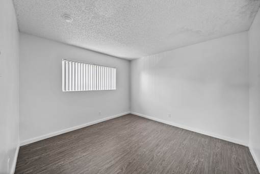 A room with a window and wooden flooring.
