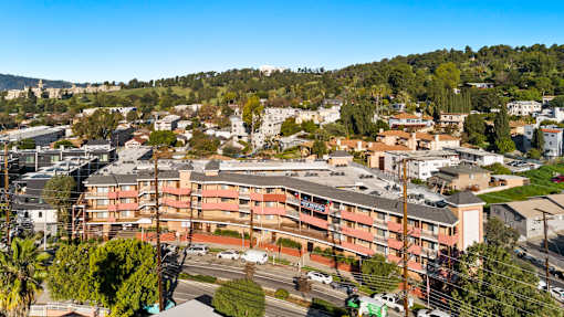 A large apartment complex is surrounded by trees and other buildings.