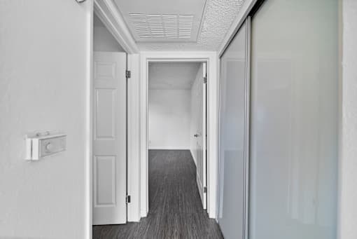 A hallway with a white door and a white wall.