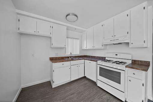 A kitchen with white cabinets and a white stove top oven.