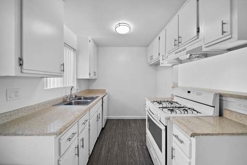 A kitchen with white cabinets and a white stove top oven.