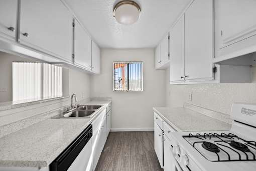 A kitchen with white cabinets and a white stove top oven.