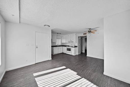 A black and white photo of a kitchen and living room.