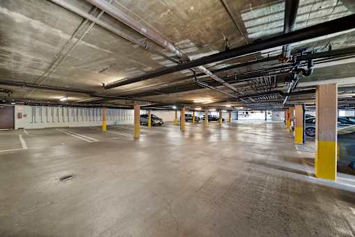 A spacious parking garage with concrete floors and yellow poles.