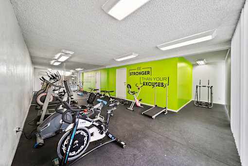A gym with exercise bikes and a sign that says "Be Stronger Than Your Excuses".