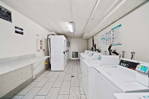A laundromat with a row of washers and dryers.