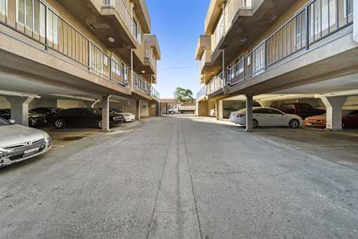 A parking lot with cars parked on both sides of the road.