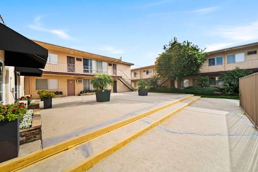 A sunny day at a residential complex with apartment buildings and potted plants.