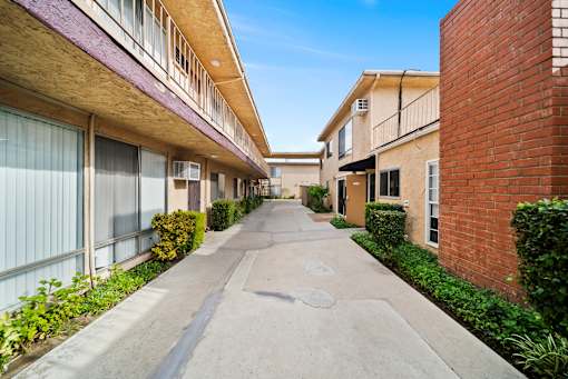 A long concrete walkway separates two rows of apartment buildings.