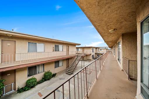 A long balcony with stairs leading to apartment buildings.