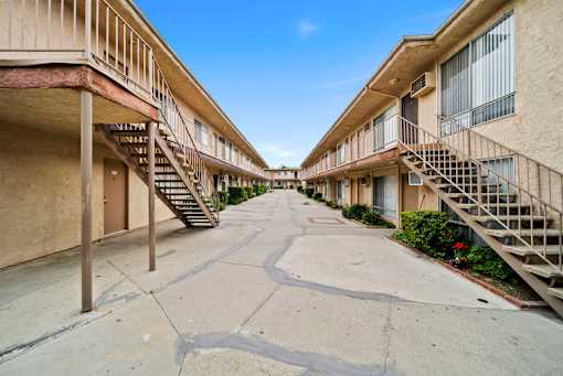 A long concrete walkway separates two rows of apartment buildings.