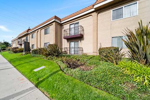 A row of apartment buildings with green lawns in front.