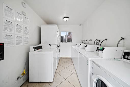 A laundromat with washers and dryers lined up.