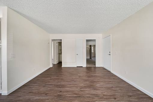 A long, empty hallway with white walls and wood flooring.