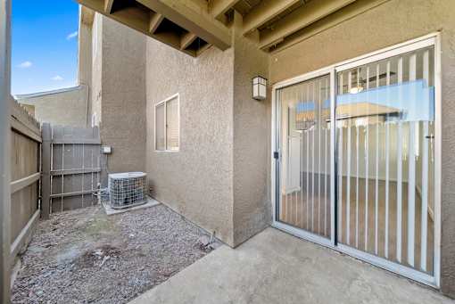 A patio area with a sliding glass door and a wall-mounted air conditioning unit.