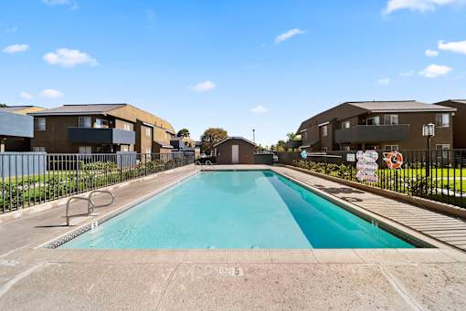 A swimming pool in front of a building with a clear blue sky.