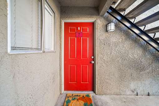 A red door with a welcome mat in front of it.
