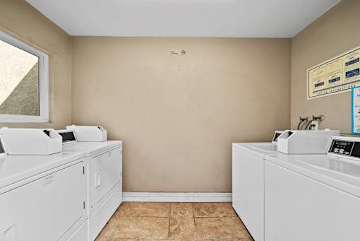 A laundry room with two washing machines and a dryer.