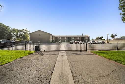 A black gate blocks the entrance to a driveway.