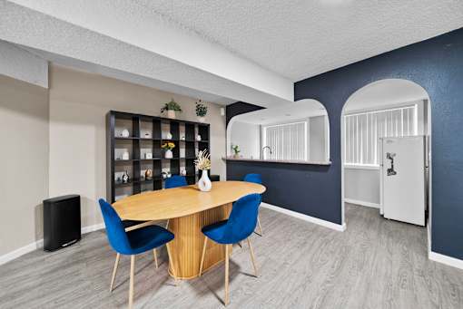 A dining area with a round table and blue chairs.