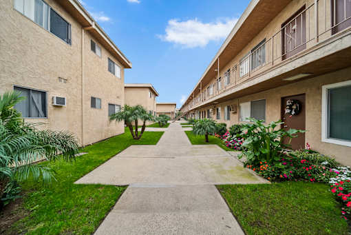 A concrete walkway leads between two rows of apartment buildings.