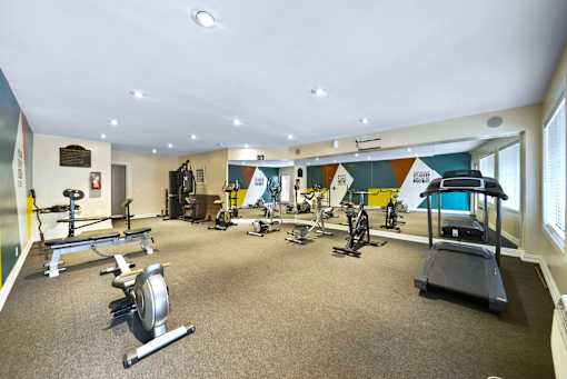 A gym with a variety of exercise equipment including treadmills, stationary bikes, and weight machines.