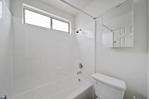 A white bathroom with a tub, toilet and sink.