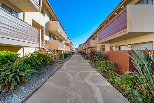 A concrete pathway leads through a row of modern apartment buildings.