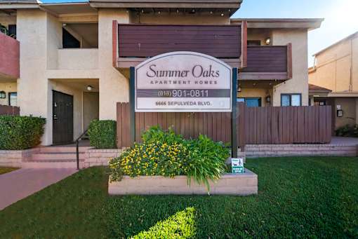 A sign for Summer Oaks Apartment Homes is displayed in front of a building.