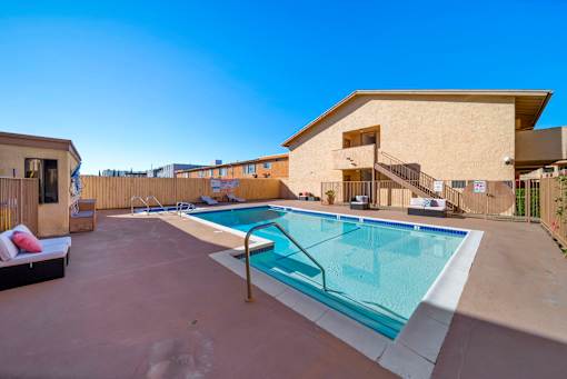 A swimming pool in a backyard with a building in the background.