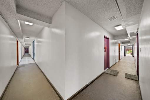 A long hallway with white walls and brown floors.