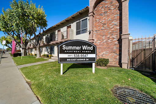 A sign for Summer Wind Apartments is in front of a brick building.