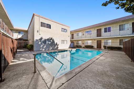 A swimming pool in front of a building with a blue sky in the background.