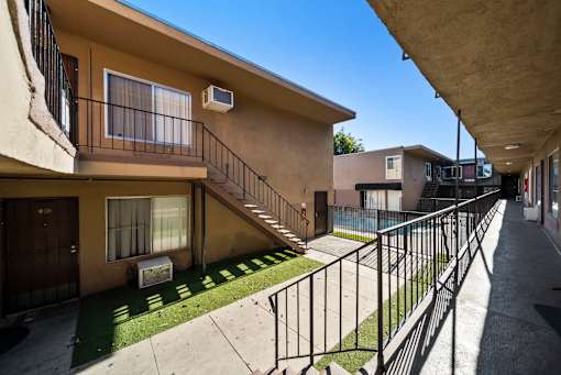 A sunny day at a residential area with apartment buildings and a metal fence.