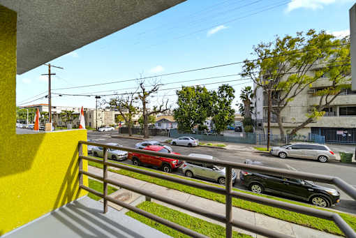 A view from a balcony looking out at a street with cars and buildings.