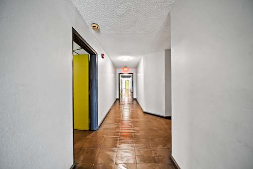 A long hallway with a yellow door on the left.