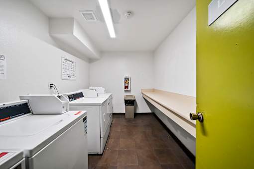 A room with a yellow door and a row of white copiers.