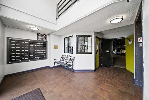 A black and white hallway with a bench and a black door.