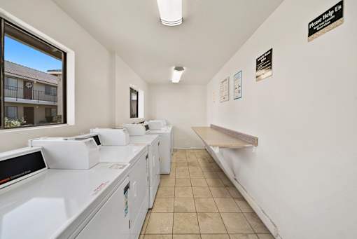 A laundromat with washers and dryers is empty except for one person.