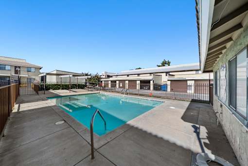 A swimming pool surrounded by a concrete deck and a metal fence.