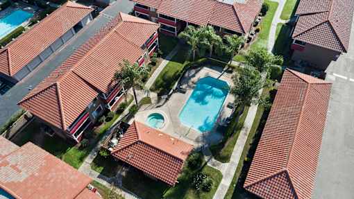 A swimming pool is surrounded by a red tiled roof.
