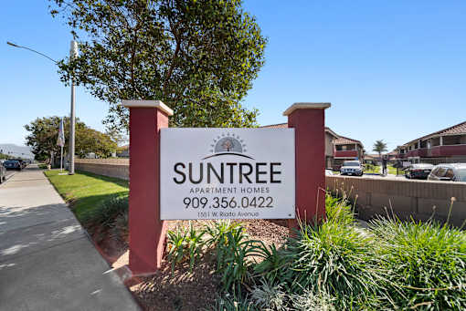 A sign for Suntree Apartment Homes stands in front of a building.