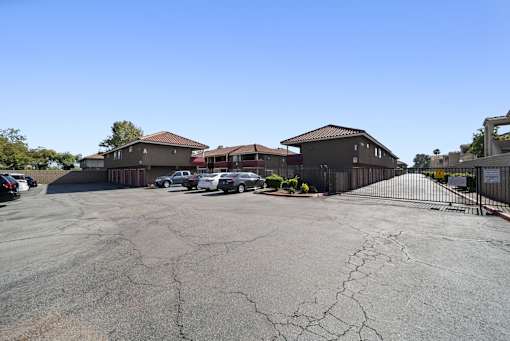 A parking lot with several cars and buildings in the background.