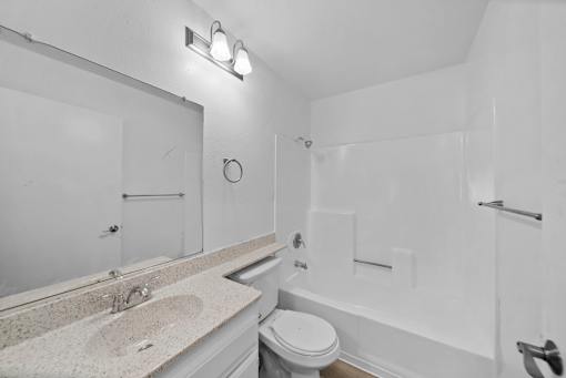 A white bathroom with a sink, toilet, and bathtub.
