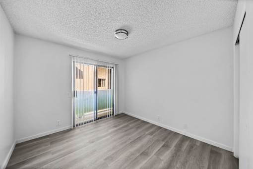 A room with a sliding glass door leading to a balcony.